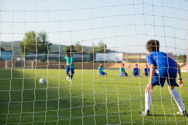 niños entrenando fútbol en un campo deportivo, simbolizando la carga horaria en la infancia