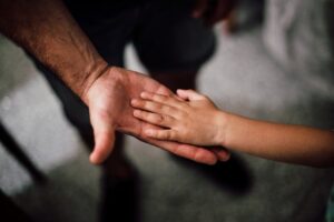 mano de un padre sosteniendo la mano de su hijo como símbolo de confianza y comunicación