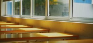 aula amb taules buides i llum natural entrant per la finestra, símbol d’oportunitats educatives